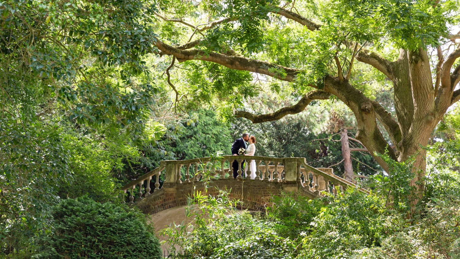 Bride & Groom on a stone bridge surrounded by trees